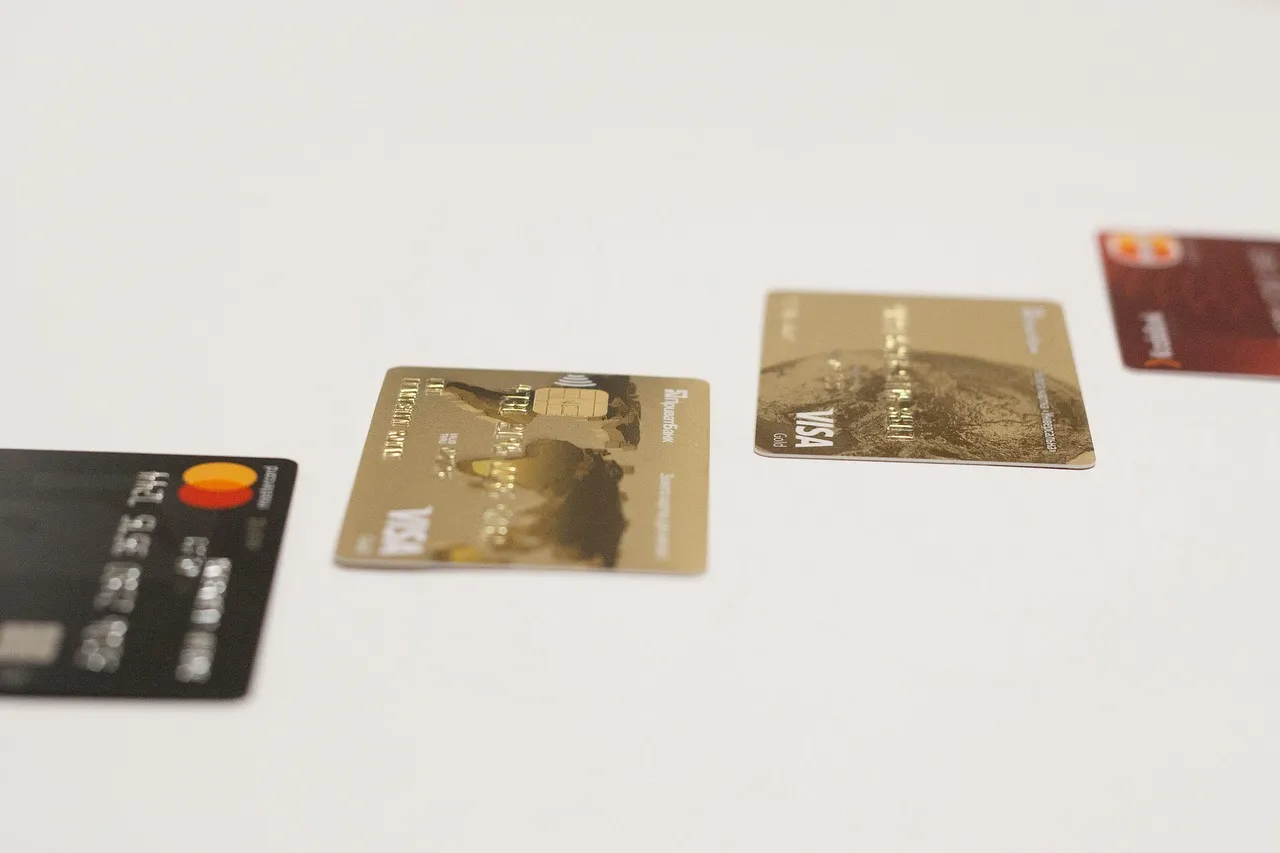 Three credit cards, including Visa and Mastercard, arranged on a white surface.