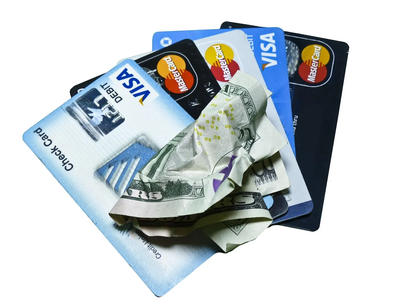 Various credit cards and crumpled cash arranged together, representing financial transactions.