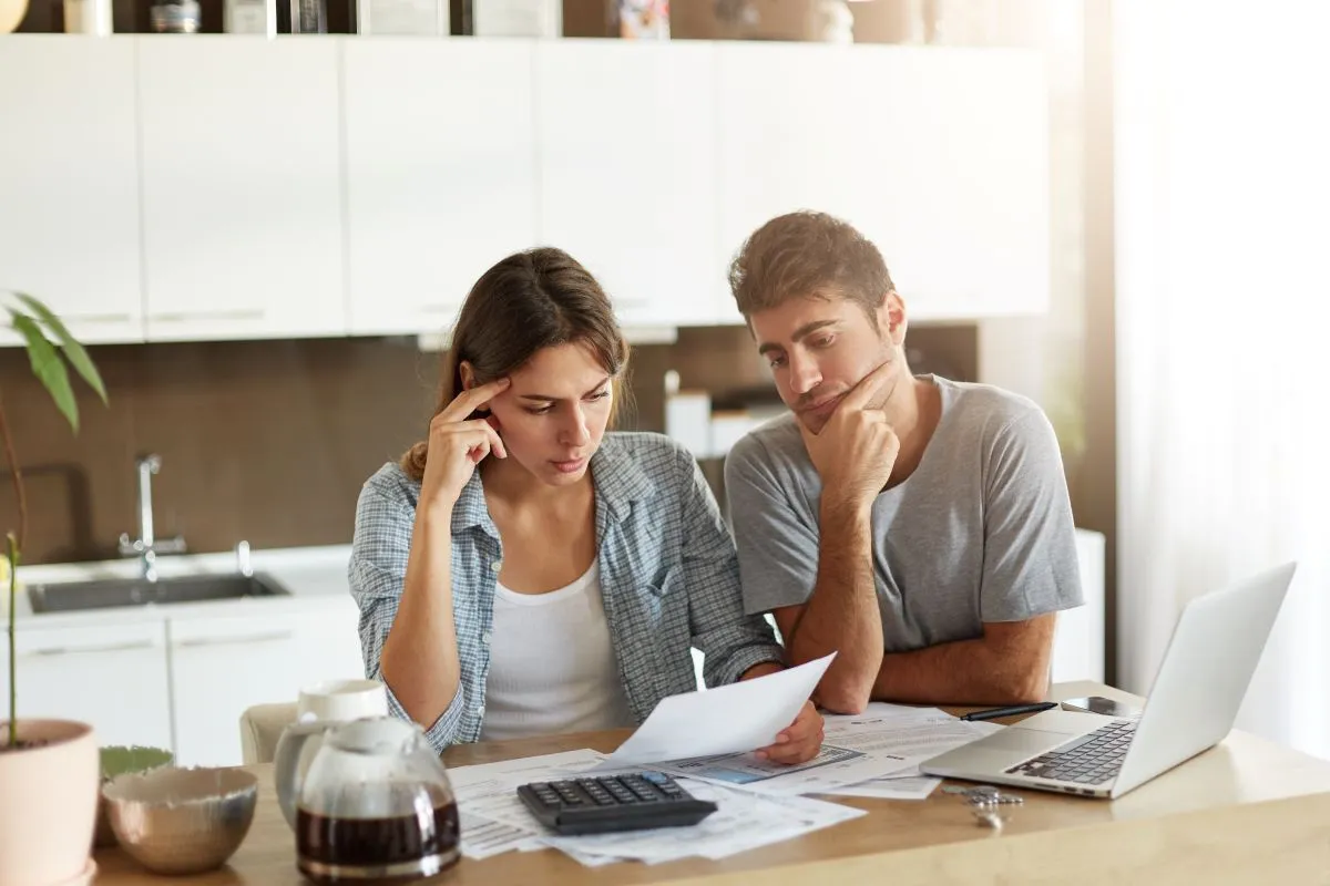 Couple reviewing financial documents and using a calculator at home.