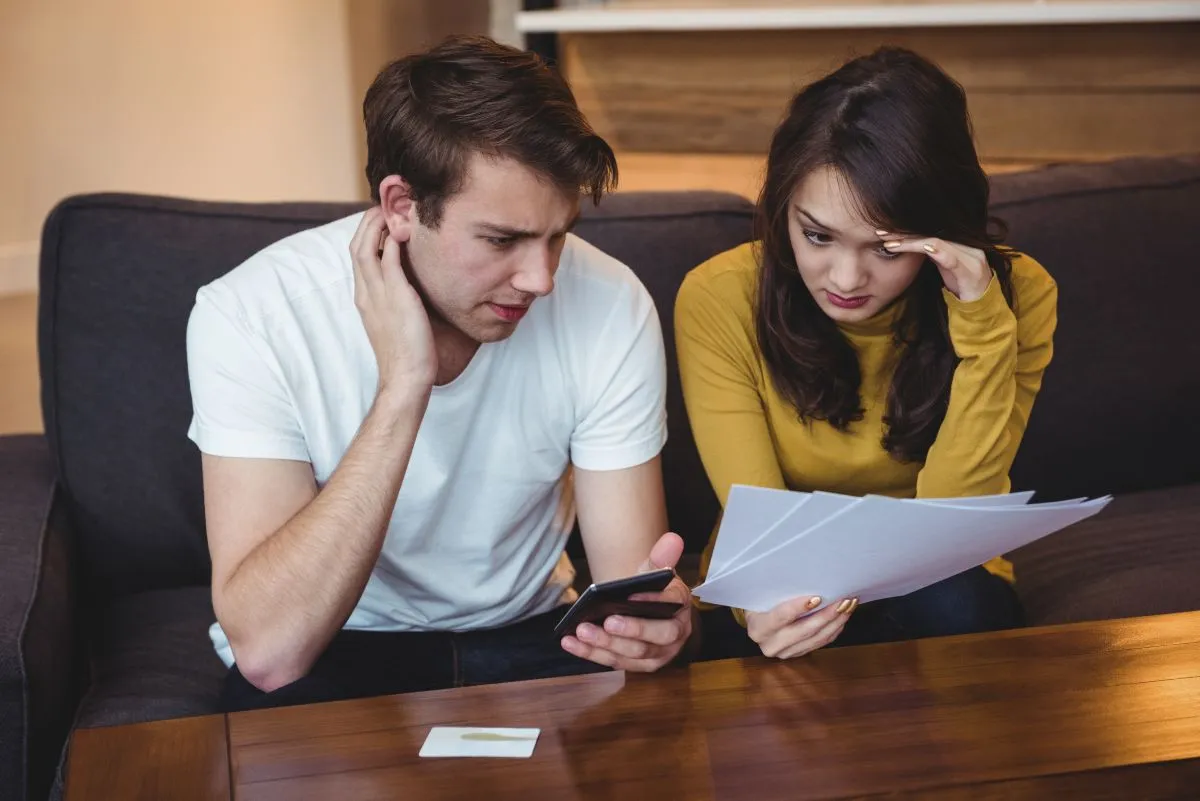 couple sitting sofa discussing with financial documents living room