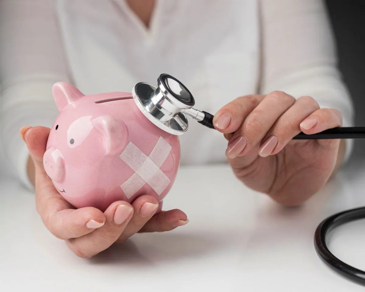 person putting stethoscope piggy bank