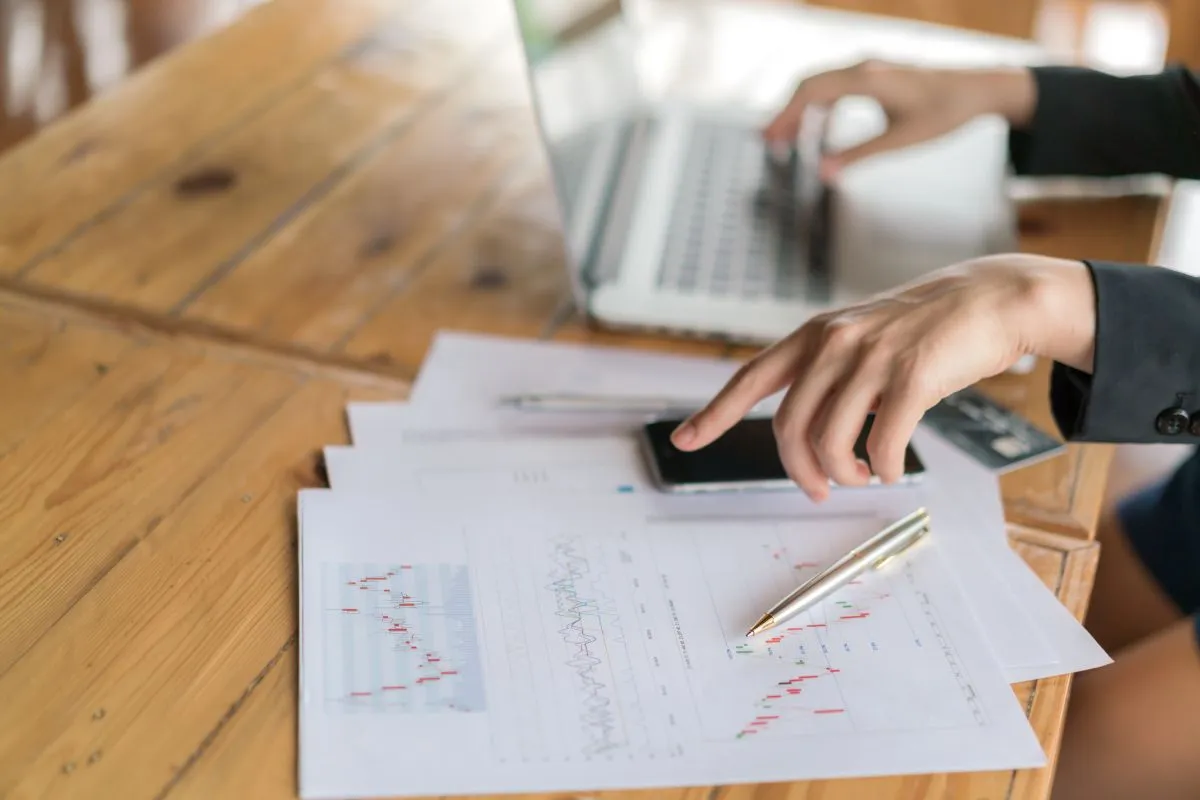 business woman hand with financial charts laptop table