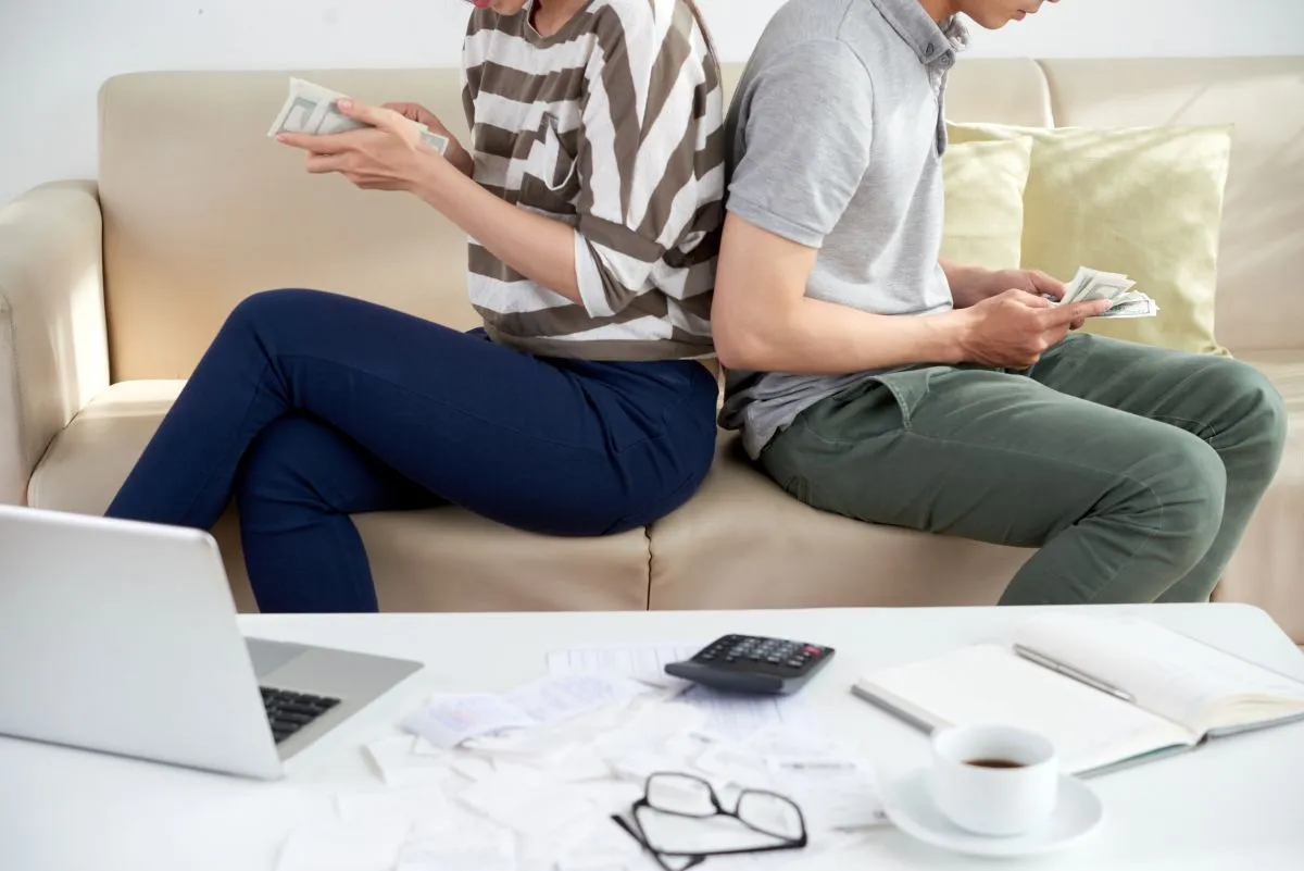 cropped couple counting money sitting back back couch